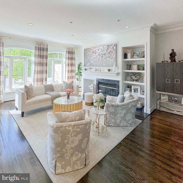 living area with crown molding, a high end fireplace, built in shelves, and hardwood / wood-style flooring