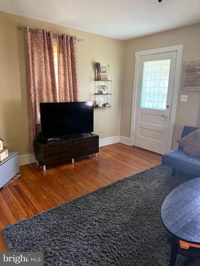 living room featuring wood finished floors, a textured ceiling, and baseboards