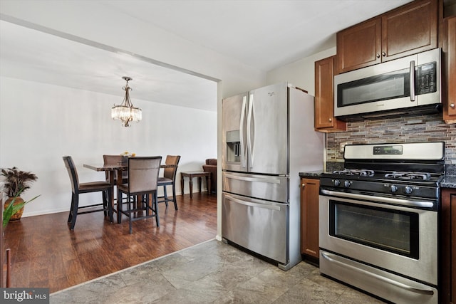 kitchen featuring decorative backsplash, pendant lighting, a chandelier, stone finish flooring, and appliances with stainless steel finishes