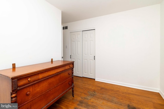 bedroom featuring baseboards, a closet, dark wood-style floors, and visible vents
