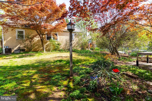 view of yard with central AC and fence