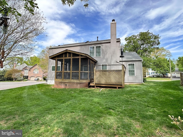 back of house featuring a chimney, a sunroom, and a yard