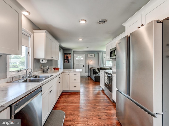 724 Webb St, Aberdeen, MD 21001 - kitchen with appliances with stainless steel finishes, white cabinetry, light countertops, dark wood-style flooring, and a peninsula