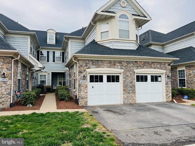 view of front of property featuring roof with shingles, aphalt driveway, and stone siding
