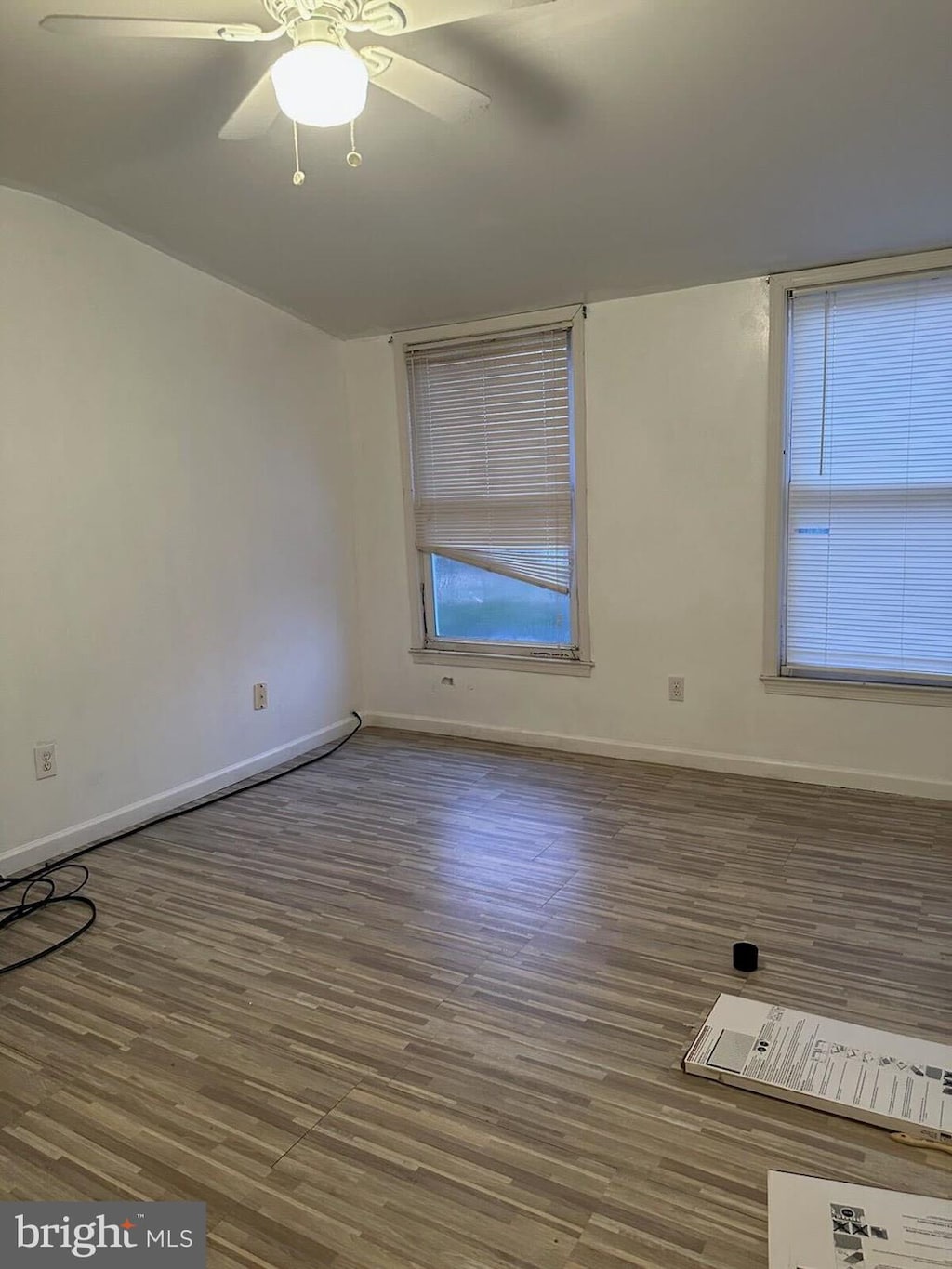 unfurnished room featuring wood finished floors, ceiling fan, and baseboards