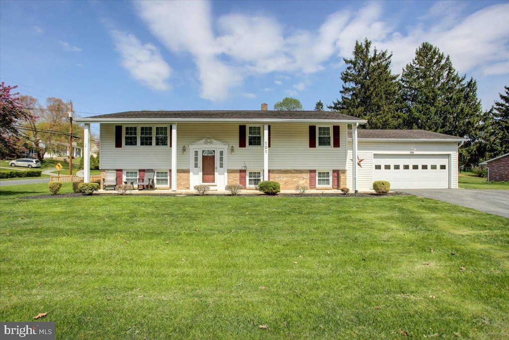 split foyer home featuring an attached garage, driveway, and a front yard