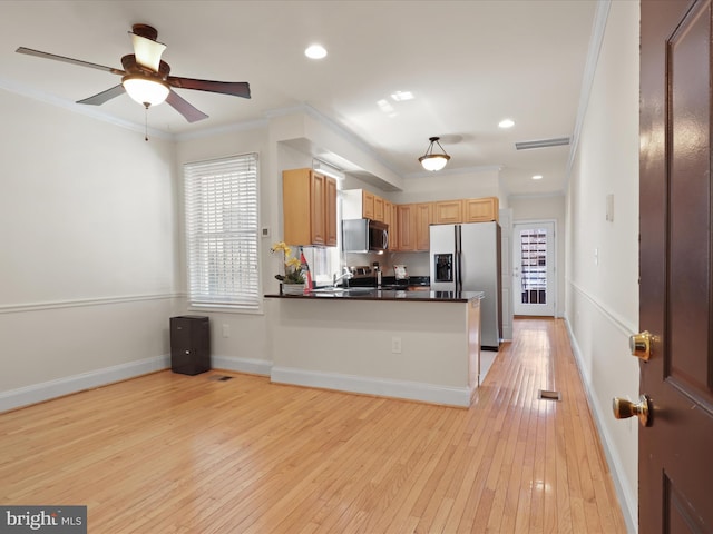 kitchen featuring dark countertops, stainless steel appliances, light wood finished floors, a peninsula, and ornamental molding