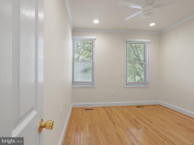 unfurnished room featuring a ceiling fan, hardwood / wood-style floors, baseboards, ornamental molding, and visible vents