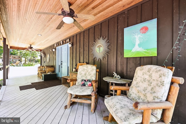 exterior space featuring wood ceiling, wood-type flooring, a ceiling fan, and wood walls