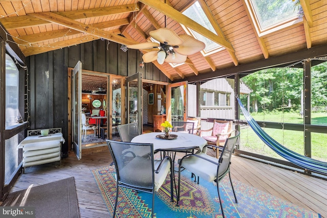 sunroom / solarium featuring a skylight, beamed ceiling, a ceiling fan, and outdoor dining area