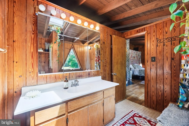 bathroom featuring wood walls, wooden ceiling, beam ceiling, and vanity