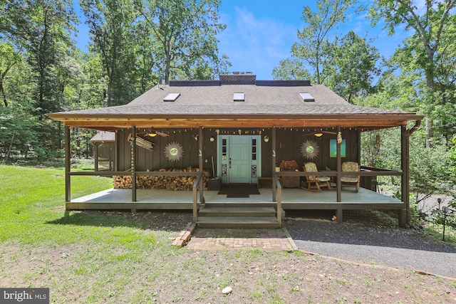 back of property featuring roof with shingles, a wooden deck, board and batten siding, and a yard