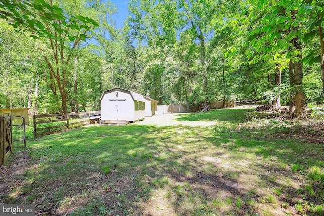view of yard with a storage shed, an outdoor structure, a wooded view, and a fenced backyard