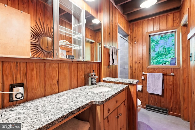 bathroom featuring visible vents, wood walls, vanity, tile patterned floors, and toilet