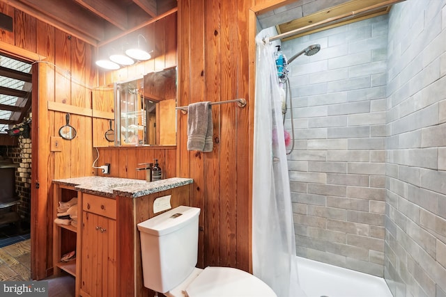 bathroom featuring toilet, wood walls, a shower stall, and vanity