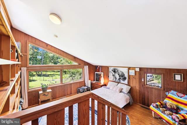 bedroom with wooden walls, visible vents, and wood finished floors