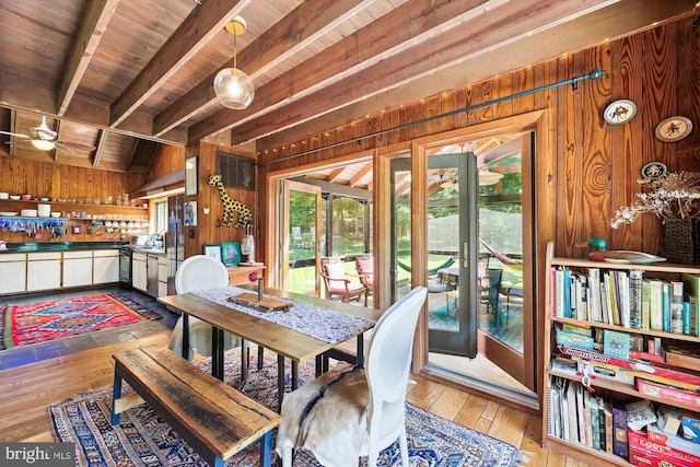 dining room featuring wood-type flooring, wood ceiling, beam ceiling, and wooden walls