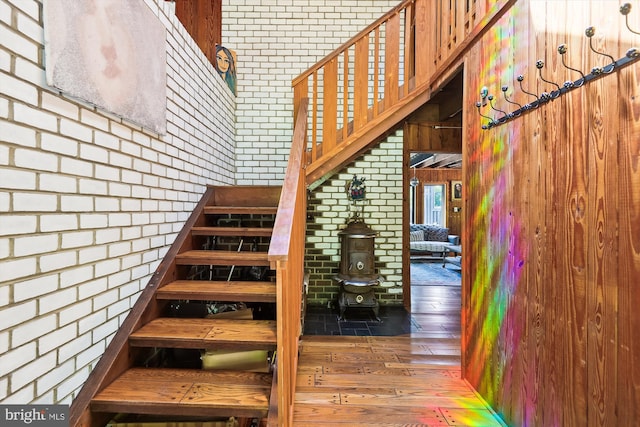 staircase featuring brick wall and hardwood / wood-style flooring
