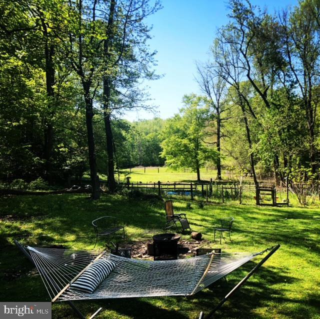 view of property's community with a lawn, fence, and a fire pit