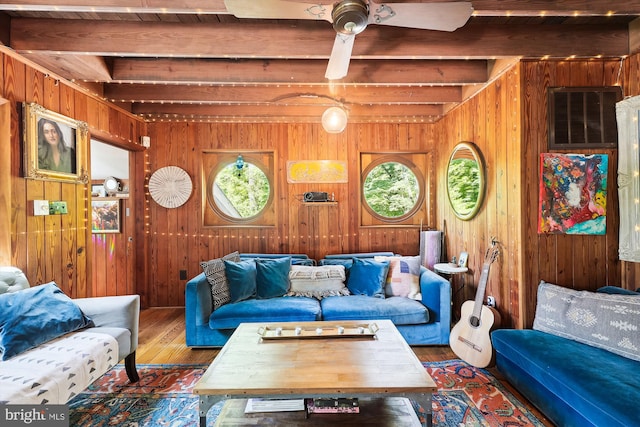 living area featuring wood-type flooring, wood walls, and beam ceiling