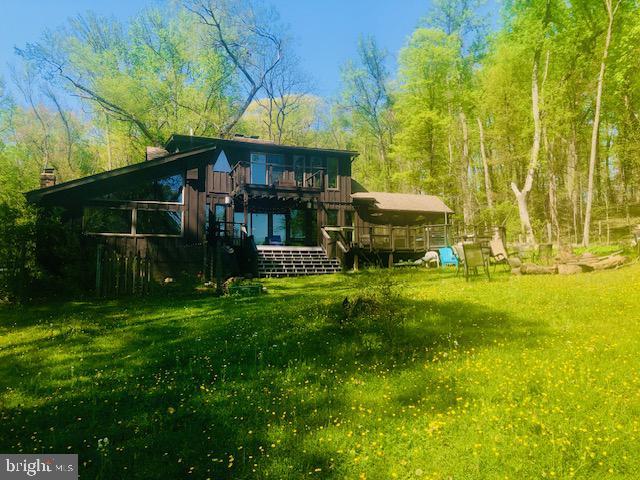 rear view of house featuring a lawn, a wooden deck, and a chimney
