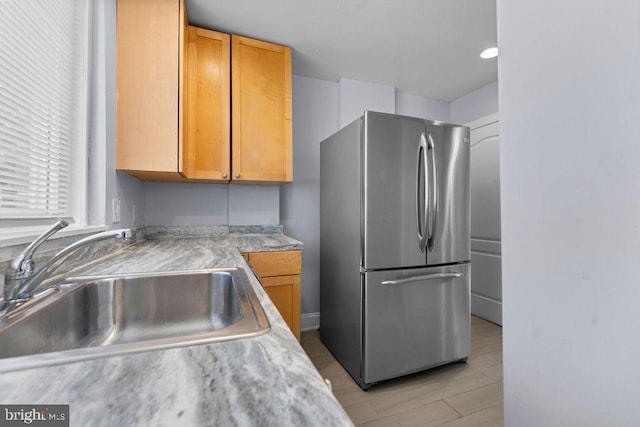 kitchen featuring light countertops, freestanding refrigerator, and a sink