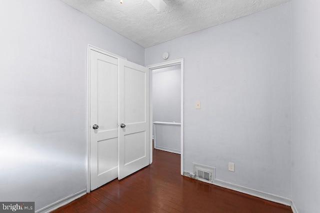 unfurnished bedroom with hardwood / wood-style floors, a textured ceiling, baseboards, and visible vents