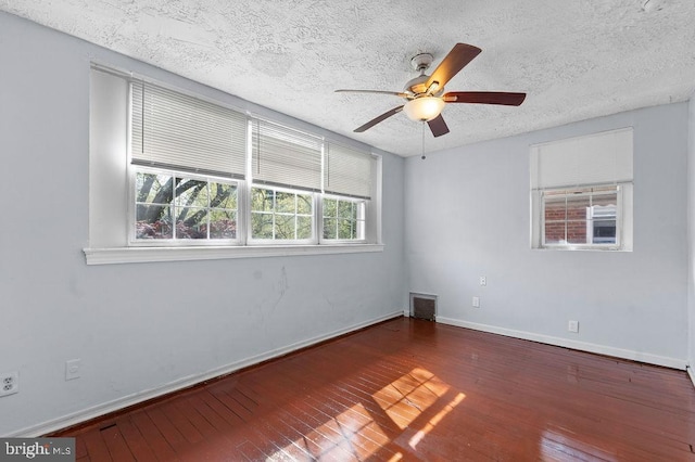empty room with a textured ceiling, baseboards, visible vents, a ceiling fan, and hardwood / wood-style flooring