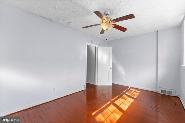 spare room with visible vents, a ceiling fan, wood-type flooring, baseboards, and a textured ceiling