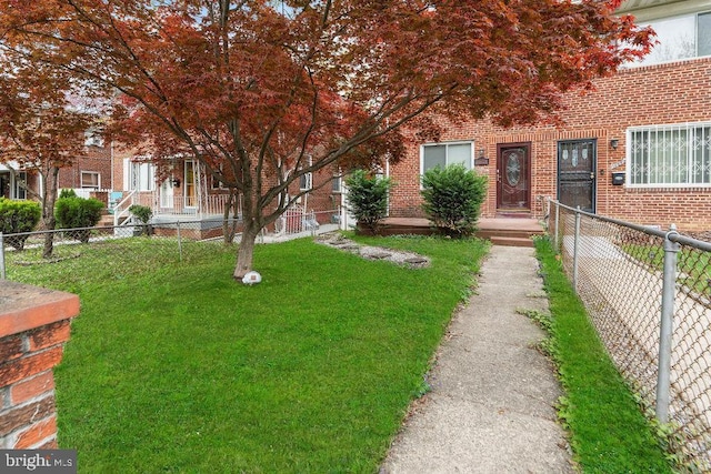 view of front of house with brick siding, a front lawn, and fence