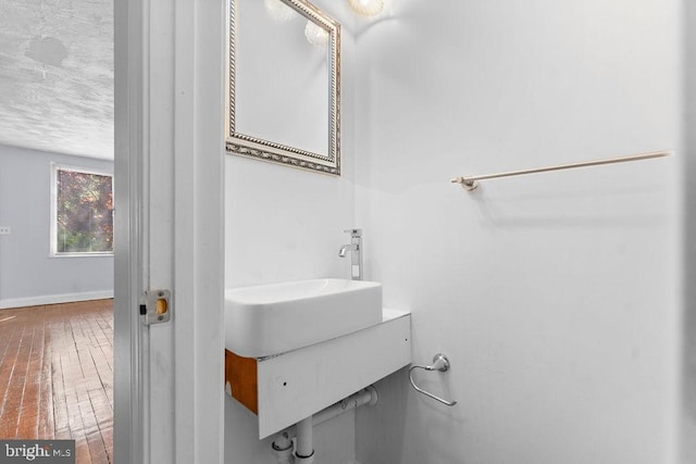 bathroom with hardwood / wood-style floors, baseboards, a textured ceiling, and vanity