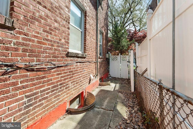 view of property exterior featuring brick siding and fence