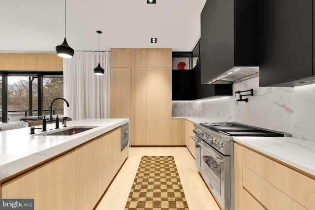 kitchen with high end stove, light brown cabinetry, light stone counters, and a sink