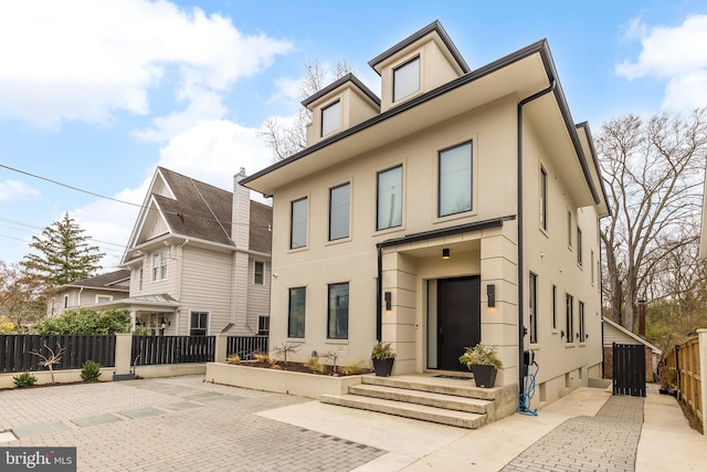 view of front of home featuring fence, a patio, and stucco siding