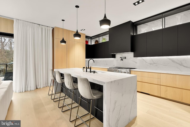 kitchen featuring modern cabinets, wall chimney range hood, range, and a sink