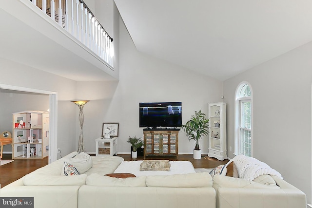 living room with high vaulted ceiling, baseboards, and wood finished floors
