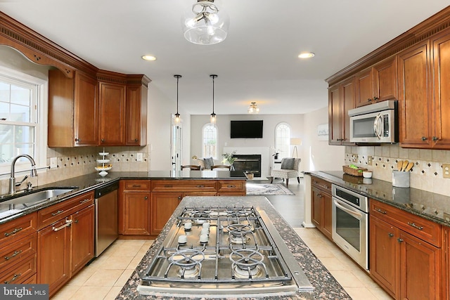 kitchen featuring open floor plan, light tile patterned floors, a sink, appliances with stainless steel finishes, and backsplash