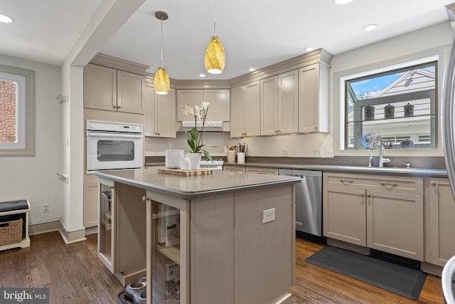 kitchen featuring dishwasher, oven, a sink, dark wood-style flooring, and a center island