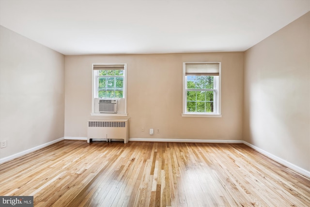 unfurnished room with radiator heating unit, hardwood / wood-style flooring, cooling unit, and baseboards