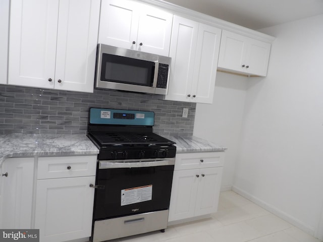 kitchen featuring white cabinets, baseboards, decorative backsplash, light stone counters, and appliances with stainless steel finishes