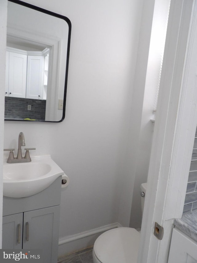 bathroom with tasteful backsplash, baseboards, toilet, and vanity