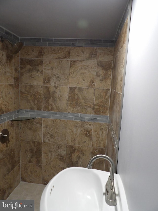 full bath with a sink and tiled shower