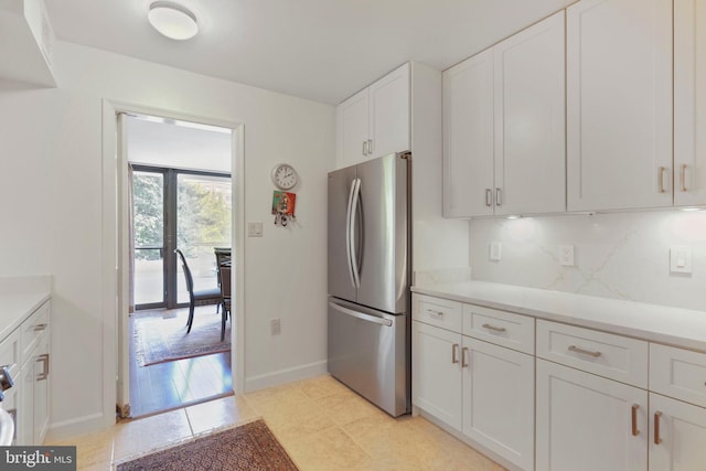 4200 Massachusetts Ave NW Unit 106, Washington, DC 20016 - kitchen with freestanding refrigerator, white cabinets, light countertops, and baseboards