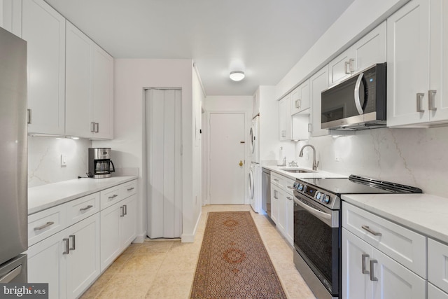 4200 Massachusetts Ave NW Unit 106, Washington, DC 20016 - kitchen with stainless steel appliances, a sink, white cabinetry, stacked washing machine and dryer, and light countertops