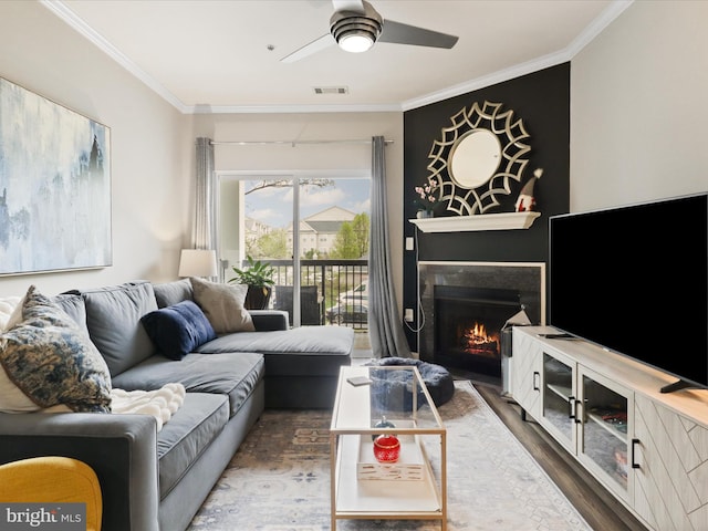 living area with wood finished floors, visible vents, and crown molding