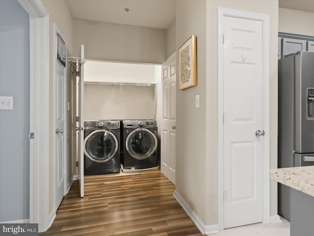 laundry area featuring wood finished floors, baseboards, washer and clothes dryer, and laundry area