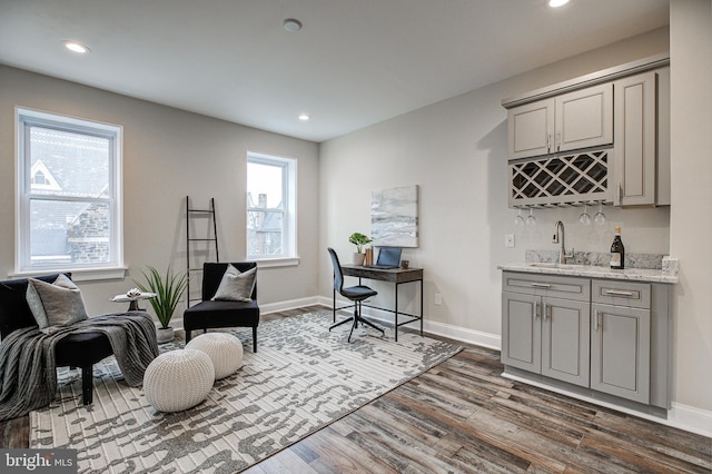 sitting room featuring bar with sink, dark wood-style flooring, recessed lighting, and baseboards