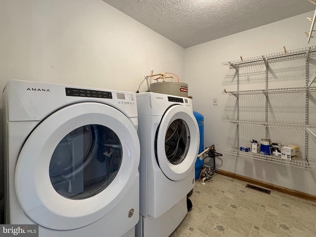 18855 Wicomico River Dr, Cobb Island, MD 20625 - laundry room with a textured ceiling, washer and clothes dryer, visible vents, water heater, and laundry area