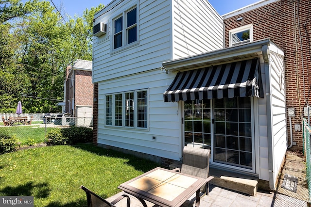 back of property with a wall mounted AC and a patio area
