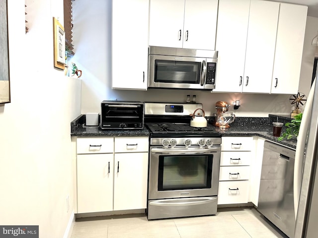 kitchen featuring white cabinets, a toaster, dark stone countertops, and appliances with stainless steel finishes